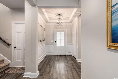 Foyer featuring a chandelier, dark wood-type flooring, stairs, a tray ceiling, and ornamental molding