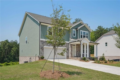 Craftsman-style house featuring driveway, an attached garage, covered porch, a front lawn, and stone siding