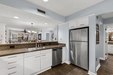 Kitchen with a textured ceiling, white cabinetry, 