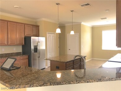Kitchen with crown molding, stainless steel fridge, plenty of natural light, dark stone countertops, and a kitchen island