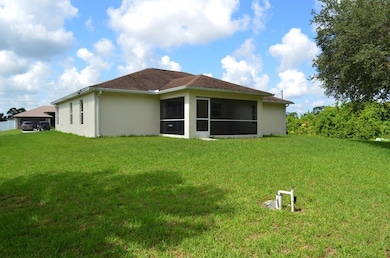 Rear view of house featuring stucco siding, a lawn, and a sunroom