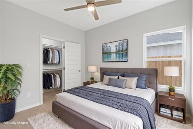 Bedroom featuring ceiling fan, a walk in closet, light wood-style flooring, baseboards, and a closet