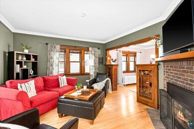 Living room with crown molding, a brick fireplace,