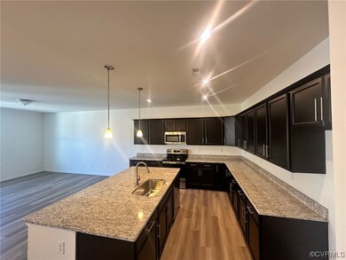 Kitchen featuring light hardwood / wood-style flooring, a center island with sink, sink, pendant lighting, and appliances with stainless steel finishes