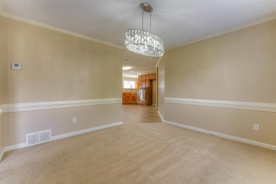 Spare room featuring light carpet, a chandelier, b