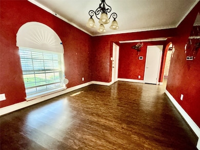 Unfurnished room with dark wood-type flooring, a chandelier, crown molding, a textured wall, and arched walkways