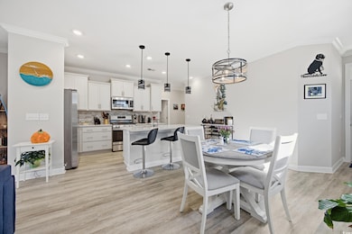 Dining area featuring crown molding, light wood finished floors, a chandelier, and recessed lighting