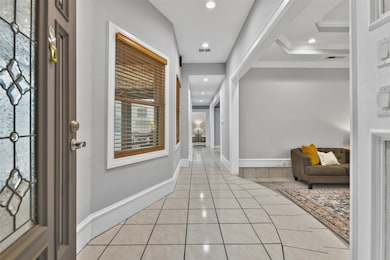 A painted wood front door with leaded glass detailing opens from the gated courtyard into an inviting foyer where you'll notice recent interior paint with oversized 9-inch baseboards, recessed lighting, and easy maintenance tile flooring.