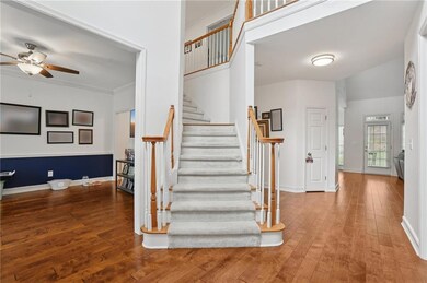 Stairway featuring hardwood / wood-style flooring, a ceiling fan, and crown molding