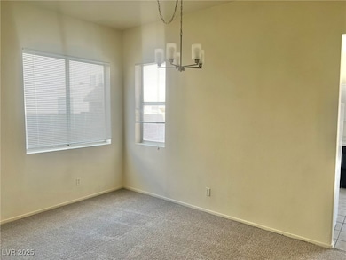 Empty room featuring carpet flooring and a chandelier