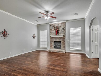 Unfurnished living room with a ceiling fan, a fireplace, arched walkways, wood-type flooring, and crown molding