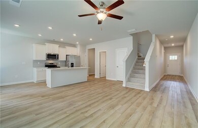 Kitchen featuring ceiling fan, white cabinets, lig