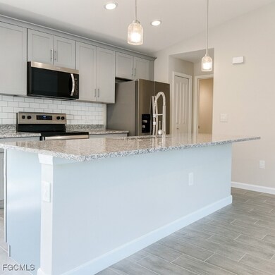 Kitchen featuring light stone countertops, appliances with stainless steel finishes, tasteful backsplash, recessed lighting, and a center island with sink