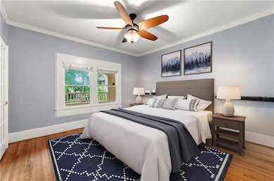 Bedroom with wood finished floors, baseboards, ornamental molding, and ceiling fan