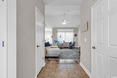 Hallway featuring vaulted ceiling, baseboards, and light tile patterned flooring
