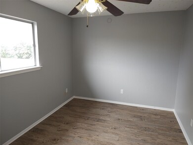 Empty room with a ceiling fan and dark wood-style floors