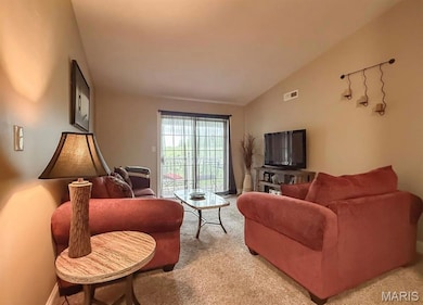 Living area with light carpet, visible vents, and lofted ceiling