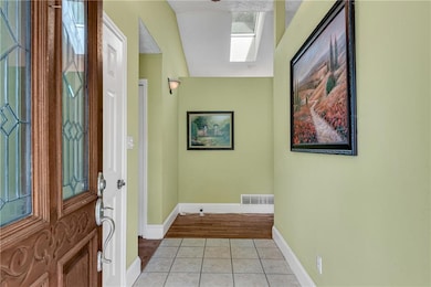Entryway with a skylight, light tile patterned flooring, and baseboards