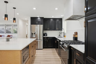 Kitchen featuring dark cabinetry, appliances with stainless steel finishes, pendant lighting, recessed lighting, and custom exhaust hood