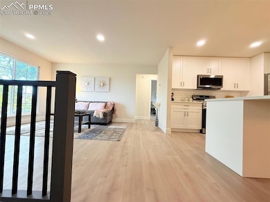 Kitchen with tasteful backsplash, appliances with stainless steel finishes, recessed lighting, white cabinets, and light wood-type flooring