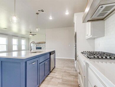 Kitchen featuring extractor fan, stainless steel appliances, blue cabinetry, ceiling fan, and tasteful backsplash