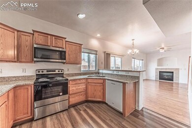 Kitchen featuring dark wood finished floors, brown cabinetry, and appliances with stainless steel finishes