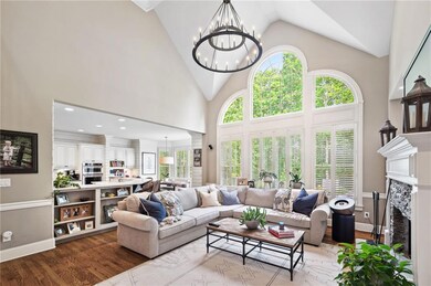 Living area featuring wood finished floors, a chandelier, a high end fireplace, and high vaulted ceiling