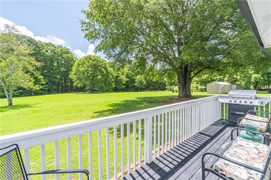 Deck with area for grilling, a yard, a storage shed, and view of scattered trees