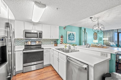 Kitchen with sink, white cabinetry, stainless steel appliances, tasteful backsplash, and kitchen peninsula