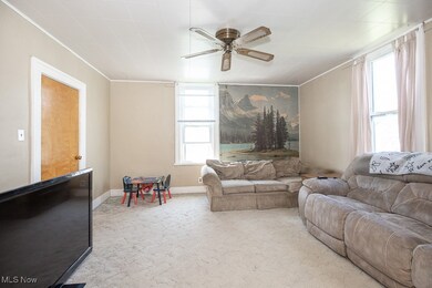 Living room with carpet floors, ornamental molding, and a ceiling fan