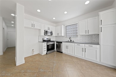 Kitchen with white tile backsplash, white cabinets