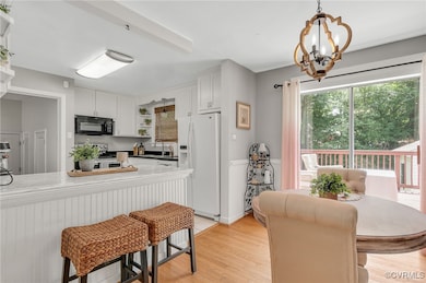 Kitchen with black microwave, white refrigerator w