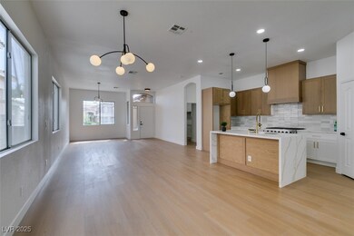 Kitchen with an inviting chandelier, light countertops, backsplash, and light wood-style floors