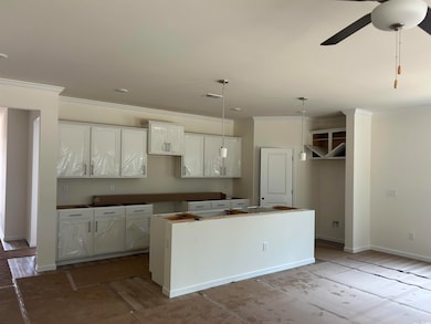 Kitchen featuring a kitchen island, ornamental molding, a ceiling fan, white cabinets, and baseboards