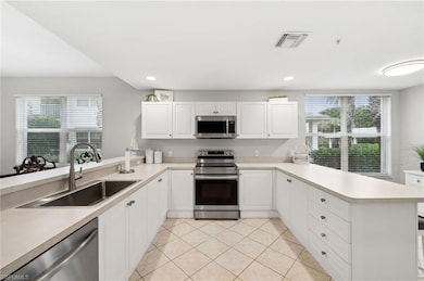Kitchen with sink, appliances with stainless steel finishes, light tile patterned floors, and kitchen peninsula