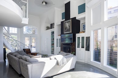 Living area featuring a high ceiling, stairway, a glass covered fireplace, ornamental molding, and french doors