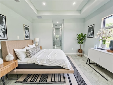 Bedroom featuring a tray ceiling, recessed lighting, and ensuite bathroom