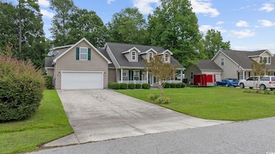 Cape cod home featuring a garage and a front lawn