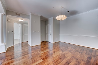 Step inside to a spacious dining area featuring warm hardwood floors, neutral tones, and abundant natural light. A statement light fixture adds the perfect touch of style and charm to the space.