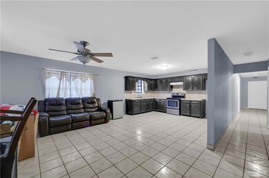 Kitchen featuring light countertops, open floor plan, electric stove, light tile patterned floors, and ceiling fan