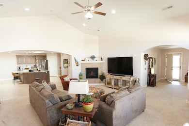 Living room featuring arched walkways, recessed lighting, ceiling fan, high vaulted ceiling, and light carpet