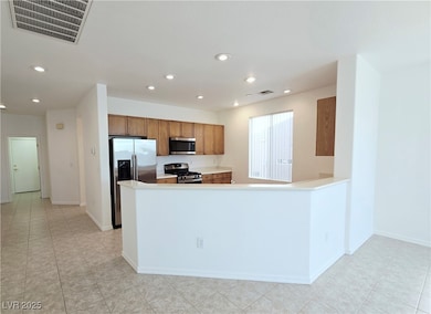 Kitchen featuring light countertops, stainless steel appliances, brown cabinets, a peninsula, and recessed lighting