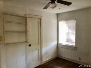 Unfurnished bedroom with ceiling fan, dark hardwoo