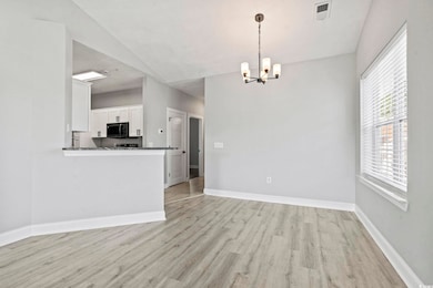 Kitchen featuring light wood-style floors, pendant lighting, white cabinets, lofted ceiling, and a chandelier