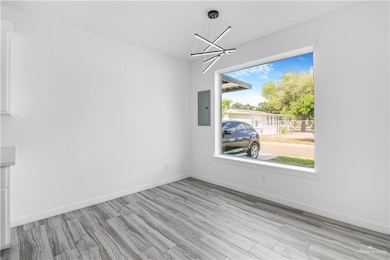 Unfurnished dining area with a chandelier, light wood finished floors, and electric panel