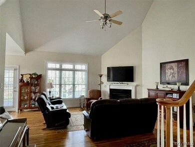 Hardwood floored living room with a ceiling fan, a