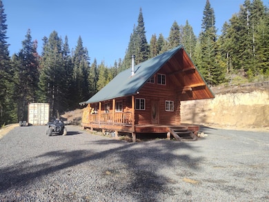 View of home's exterior with a metal roof, a porch, a forest view, log siding, and mail area
