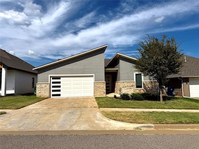 View of front of home with driveway, a front yard, brick siding, and a garage