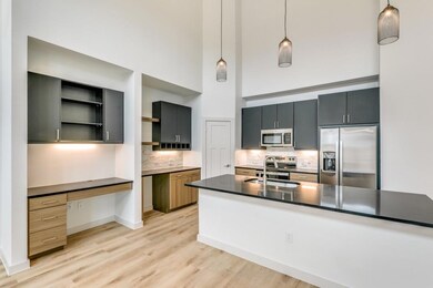 Kitchen with a sink, built in desk, a high ceiling