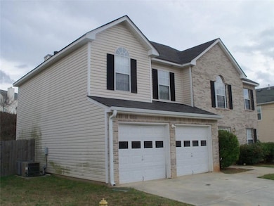 View of home's exterior featuring an attached garage, brick siding, and concrete driveway